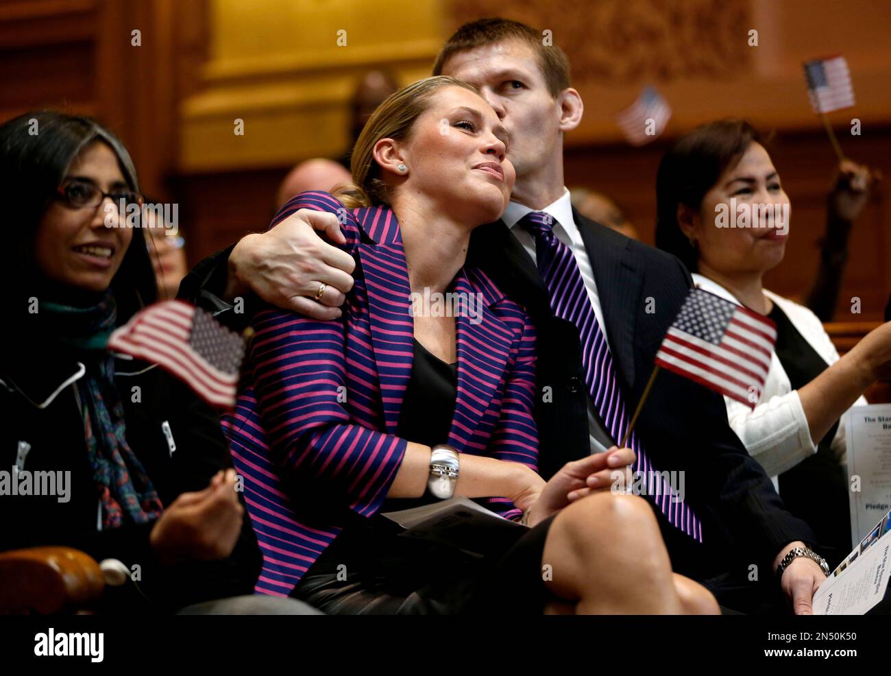 Pawell Woelke, center right, kisses his wife, Anna Woelke, of Poland, as she tears up during the playing of "God Bless the USA" after the couple took the oath to become United States citizens during a naturalization ceremony at Jersey City City Hall, Friday, April 25, 2014, in Jersey City, N.J. The U.S. Citizenship and Immigration Services claims the ceremony, in which 30 immigrants were sworn in, is the first- ever held at Jersey City City Hall. (AP Photo/Julio Cortez) Banque D'Images