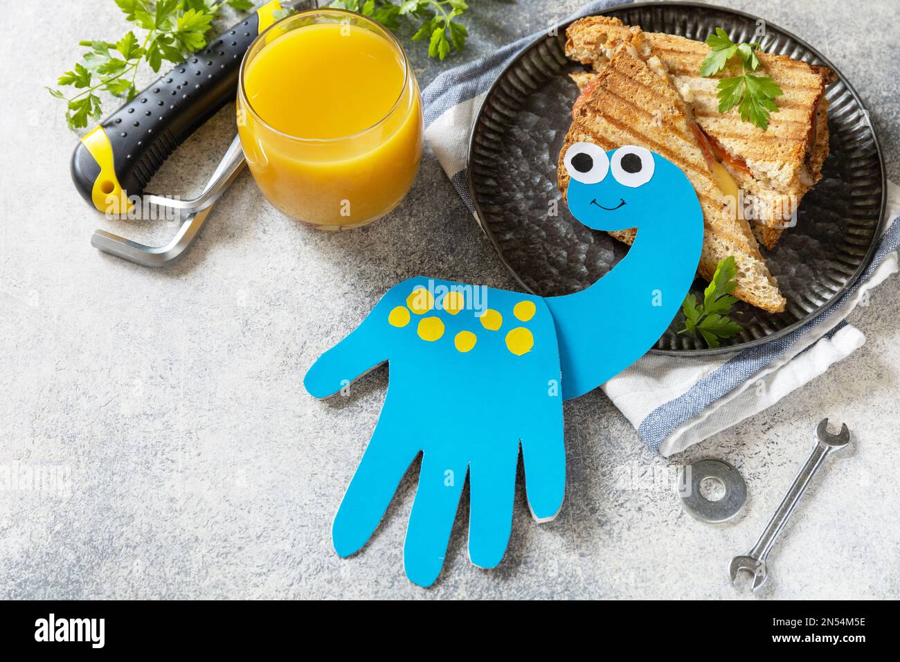 Bonne fête des pères. Carte de fête des pères dinosaure et petit déjeuner à la maison pour papa sur table en pierre grise. Copier l'espace. Banque D'Images