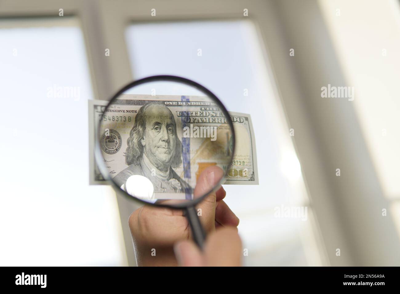 Contrefacteur forge les billets. Faux concept. Fausse monnaie dollars américains, loupe. regardez l'argent sous une loupe. filigrane, filigrane Banque D'Images