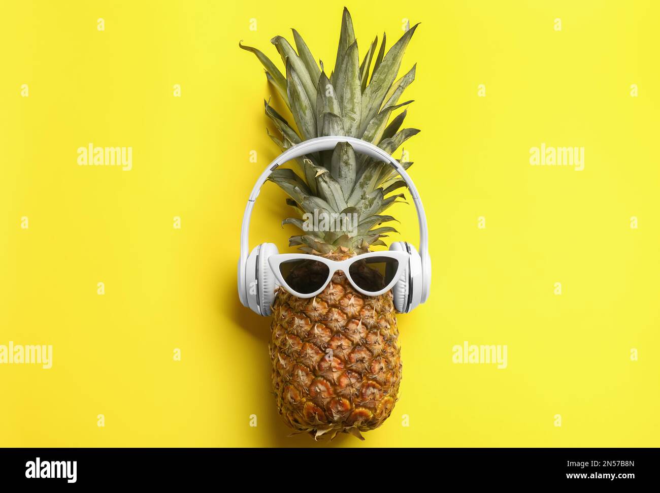 Ananas avec lunettes de soleil et écouteurs sur fond jaune, vue du dessus.  Concept créatif Photo Stock - Alamy