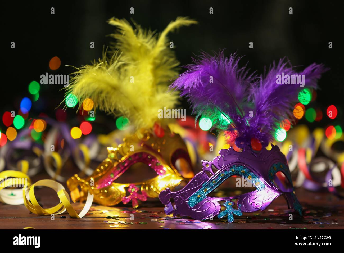 Magnifiques masques de carnaval et décoration de fête sur la table contre les lumières floues Banque D'Images