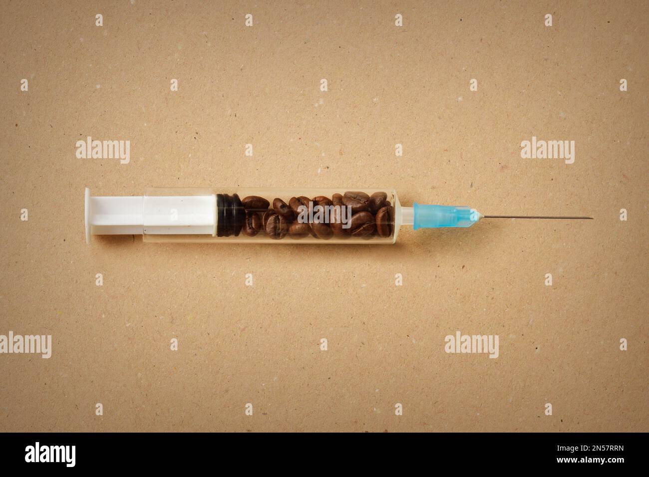 Seringue remplie de grains de café sur fond de papier recommandé Banque D'Images