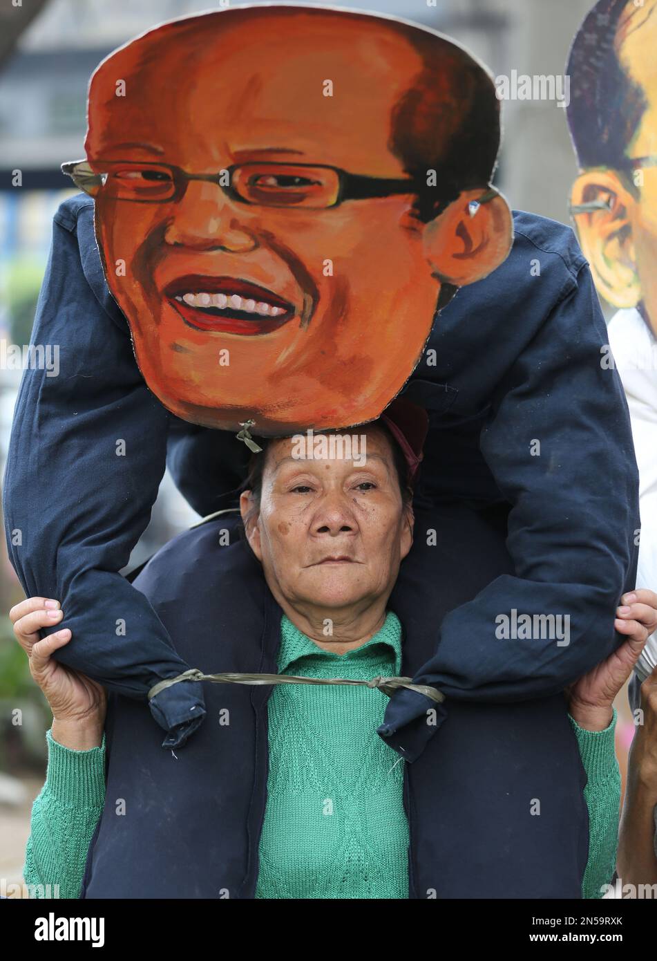A woman activist carries an effigy of Philippine President Benigno Aquino III during a rally to mark International Women's Day in Manila, Philippines on Saturday, March 8, 2014. The group are blaming President Aquino who they alleged to have neglected women and their families. (AP Photo/Aaron Favila) Banque D'Images