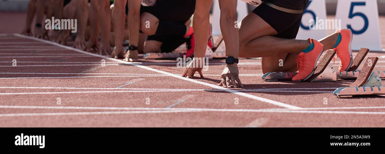 Groupe d'athlètes masculins sur les blocs de départ. Mains sur la ligne de départ. Les athlètes à la ligne de départ du sprint sur piste et sur le terrain Banque D'Images