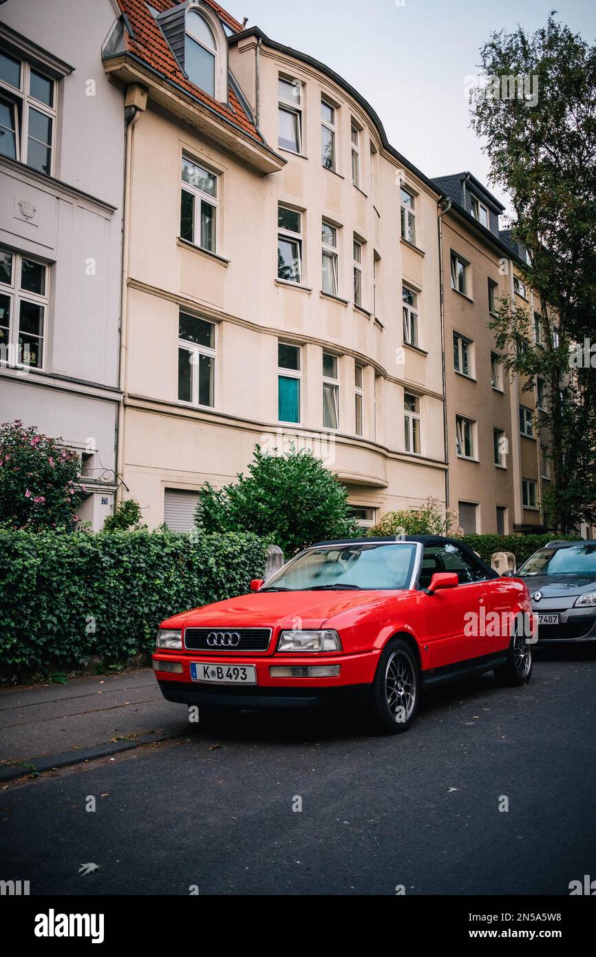 Une Audi convertible rouge est garée dans la rue en face de quelques ...