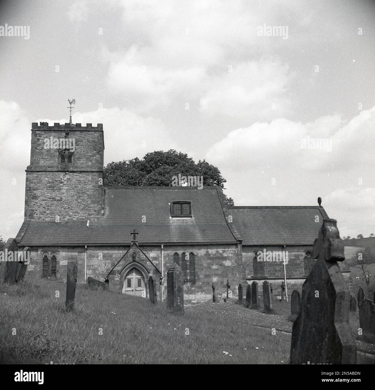 1964, historique, vue extérieure de l'église All Saints à Kirby Underdale, York, Angleterre, Royaume-Uni, avec tour de l'horloge, un lieu de travail chrétien, dont certaines parties remontent à l'époque normande. Banque D'Images