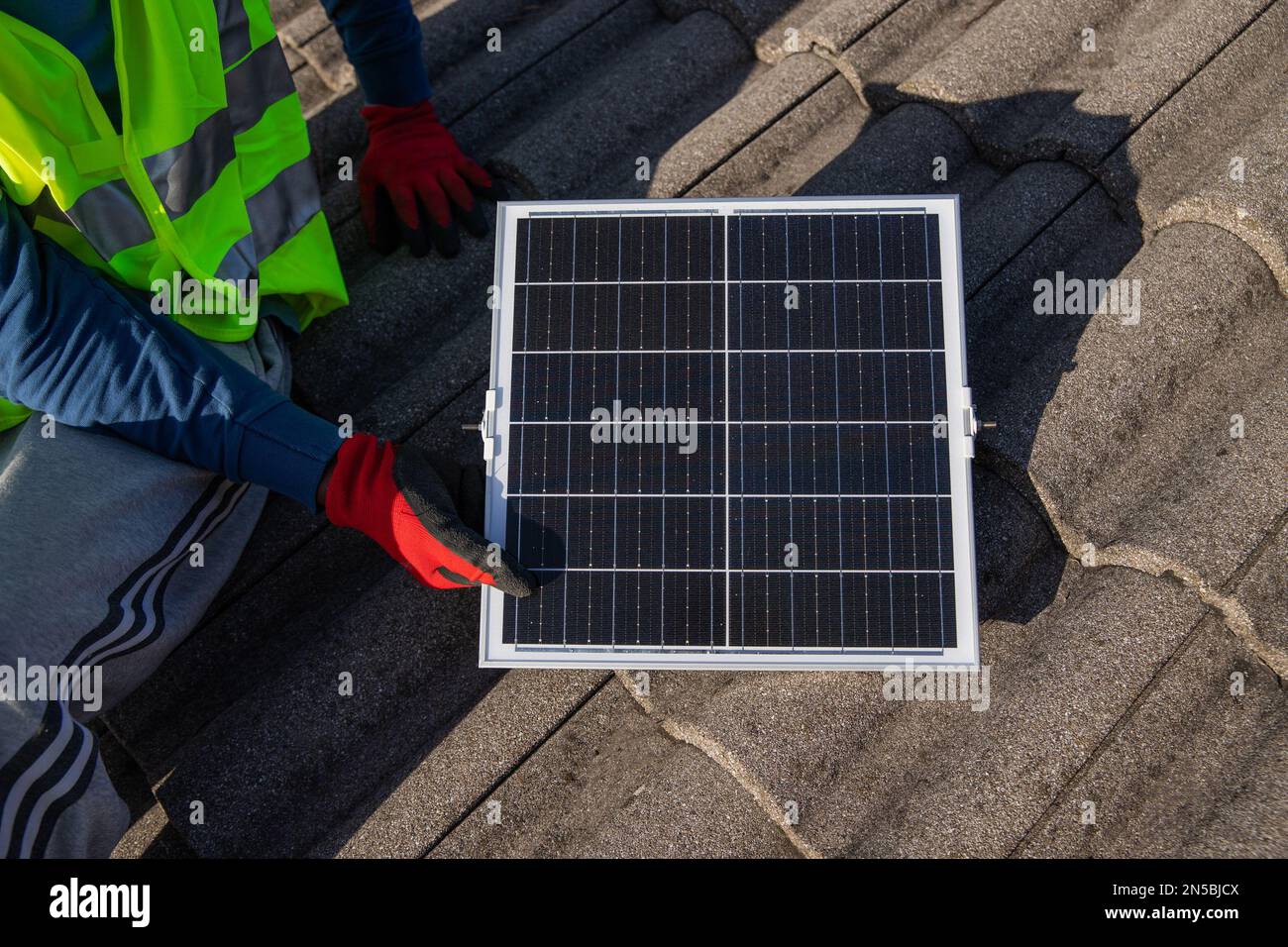 Un technicien installe un panneau solaire photovoltaïque sur un toit, énergie durable. Banque D'Images