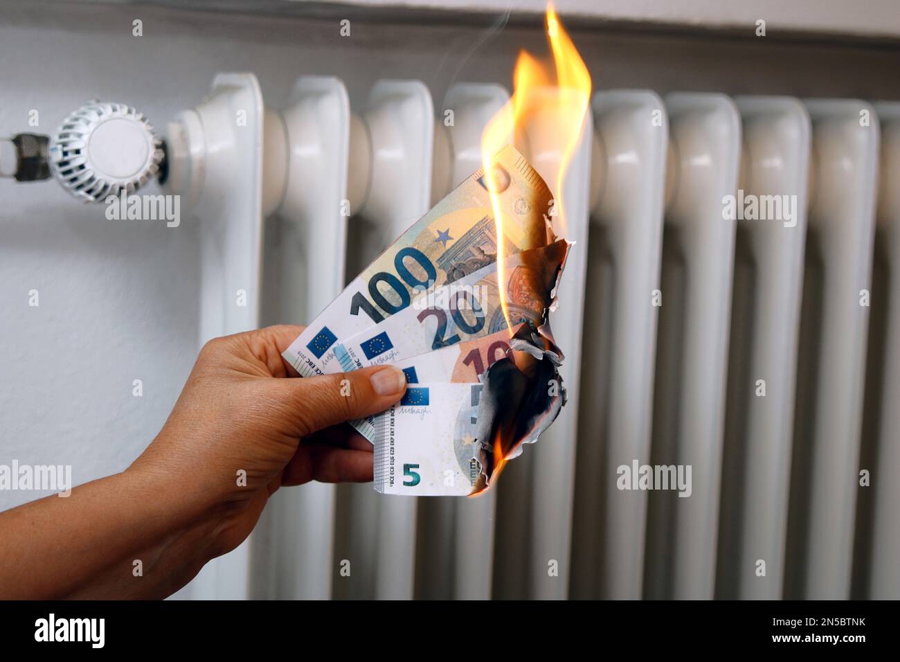 Main avec des factures d'euros brûlantes, l'augmentation de prix du chauffage Banque D'Images