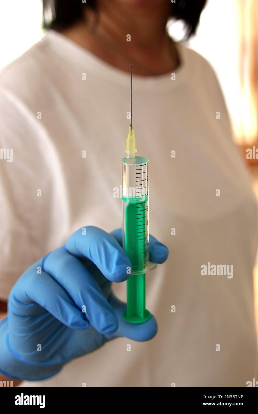 seringue en plastique jetable avec aiguille jetable dans la main avec un gant médical Banque D'Images