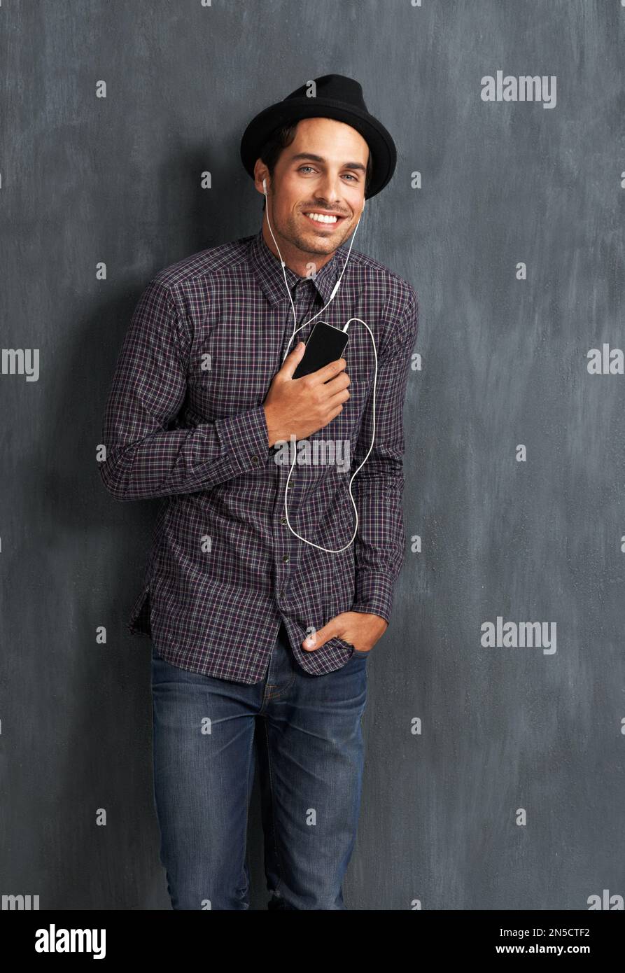 Écouter de la musique. Portrait d'un jeune homme branché qui écoute de la musique sur son mobile. Banque D'Images