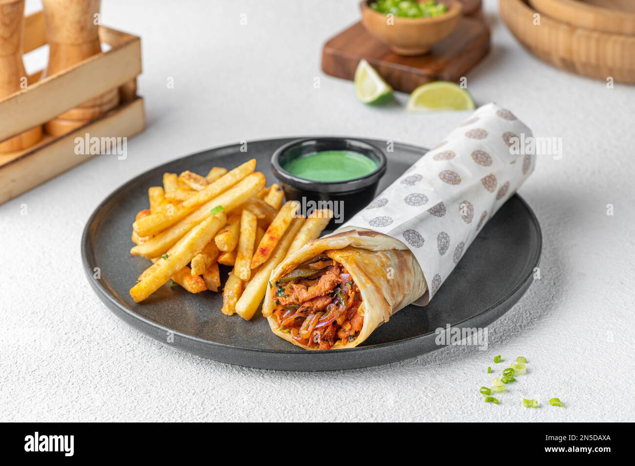 Des tacos roulés de style mexicain servis avec des frites dorées et une sauce crémeuse Banque D'Images