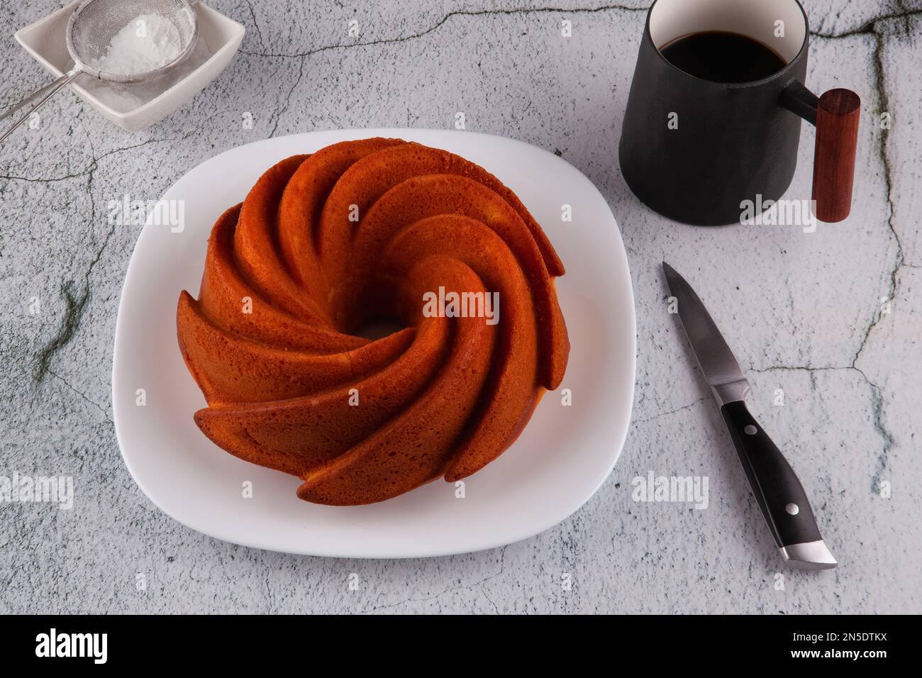 Gâteau rond d'amande et de farine de riz sur la serviette de thé rayée et la table en marbre.petit déjeuner avec une tasse de café. Banque D'Images