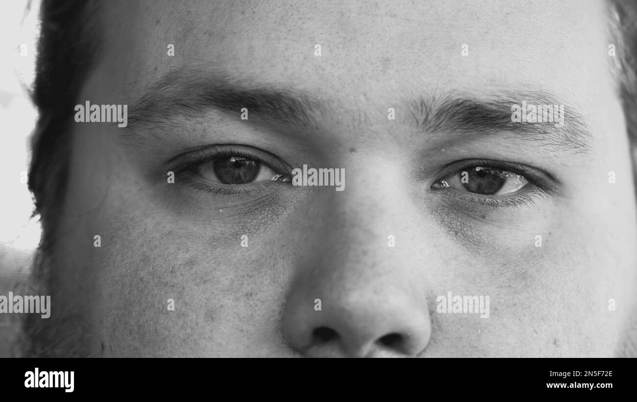 Un jeune homme souriant à la caméra en noir et blanc monochromatique. Macro yeux Banque D'Images