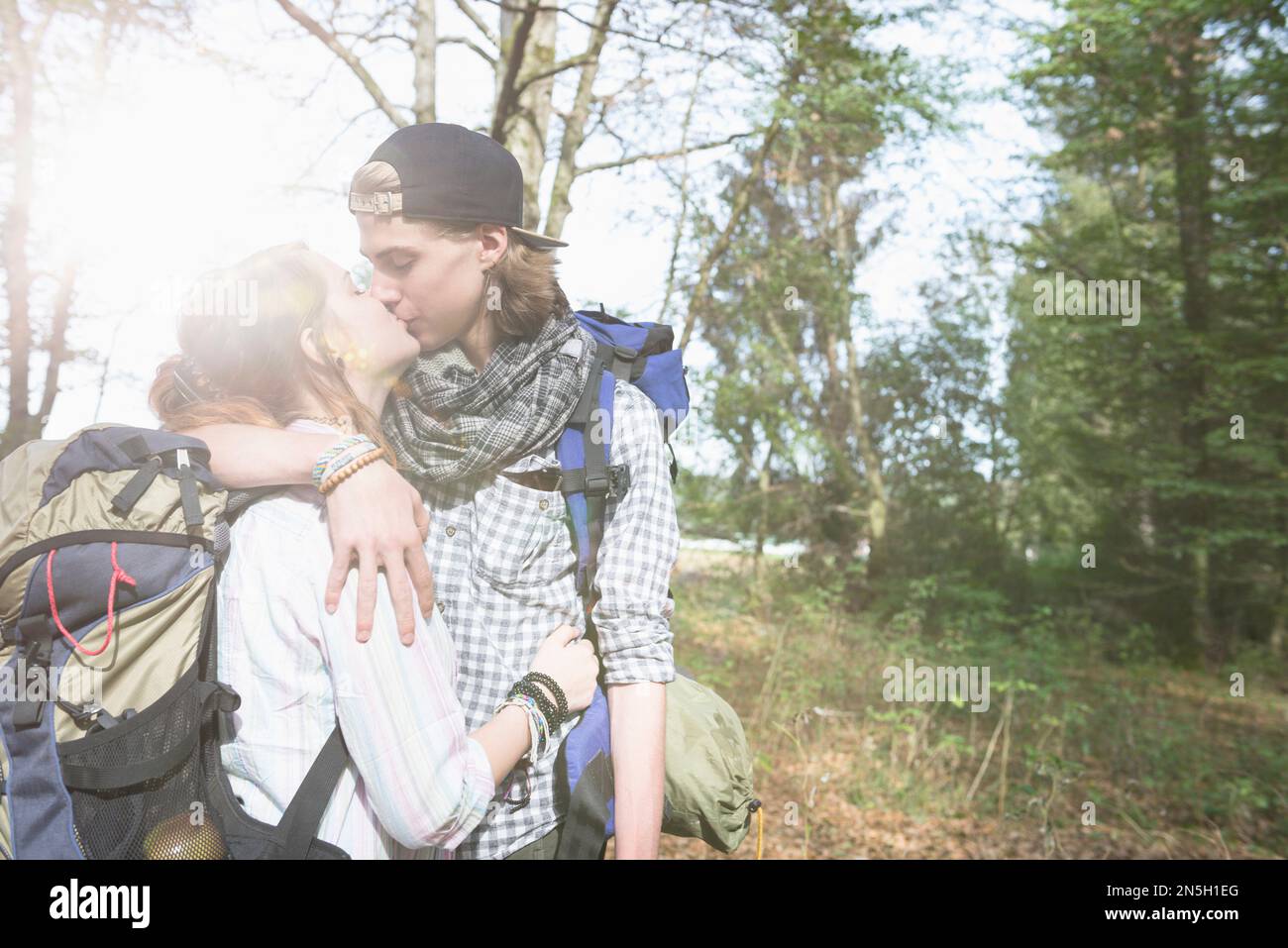 Jeune couple randonnée avec sac à dos et embrassant dans une forêt, Bavière, Allemagne Banque D'Images
