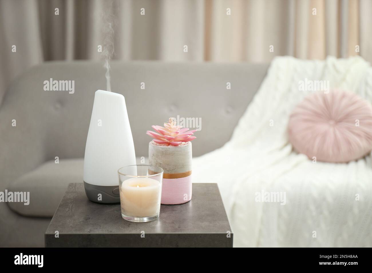 Diffuseur d'huile aromatique et bougie sur table dans la chambre Banque D'Images