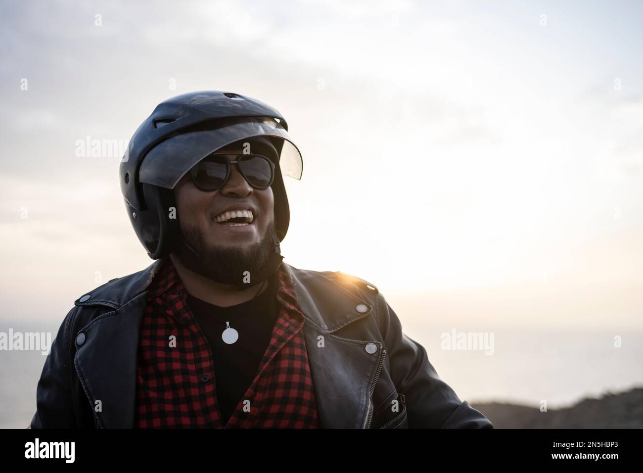 Motard barbu souriant au coucher du soleil. Banque D'Images