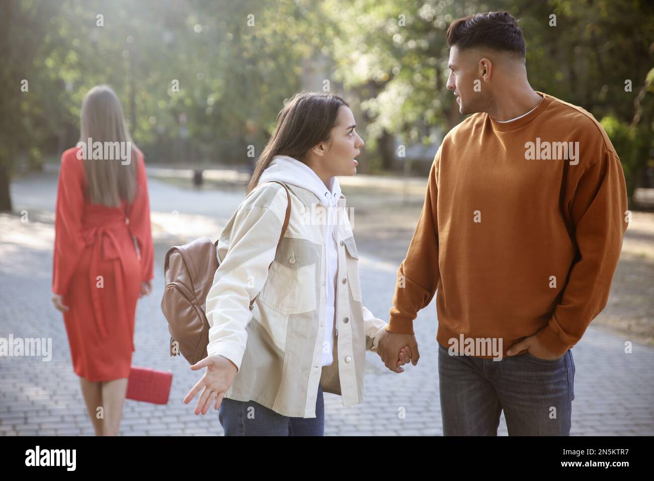 Homme disloyal regardant une autre femme en marchant avec sa petite amie dans le parc Banque D'Images