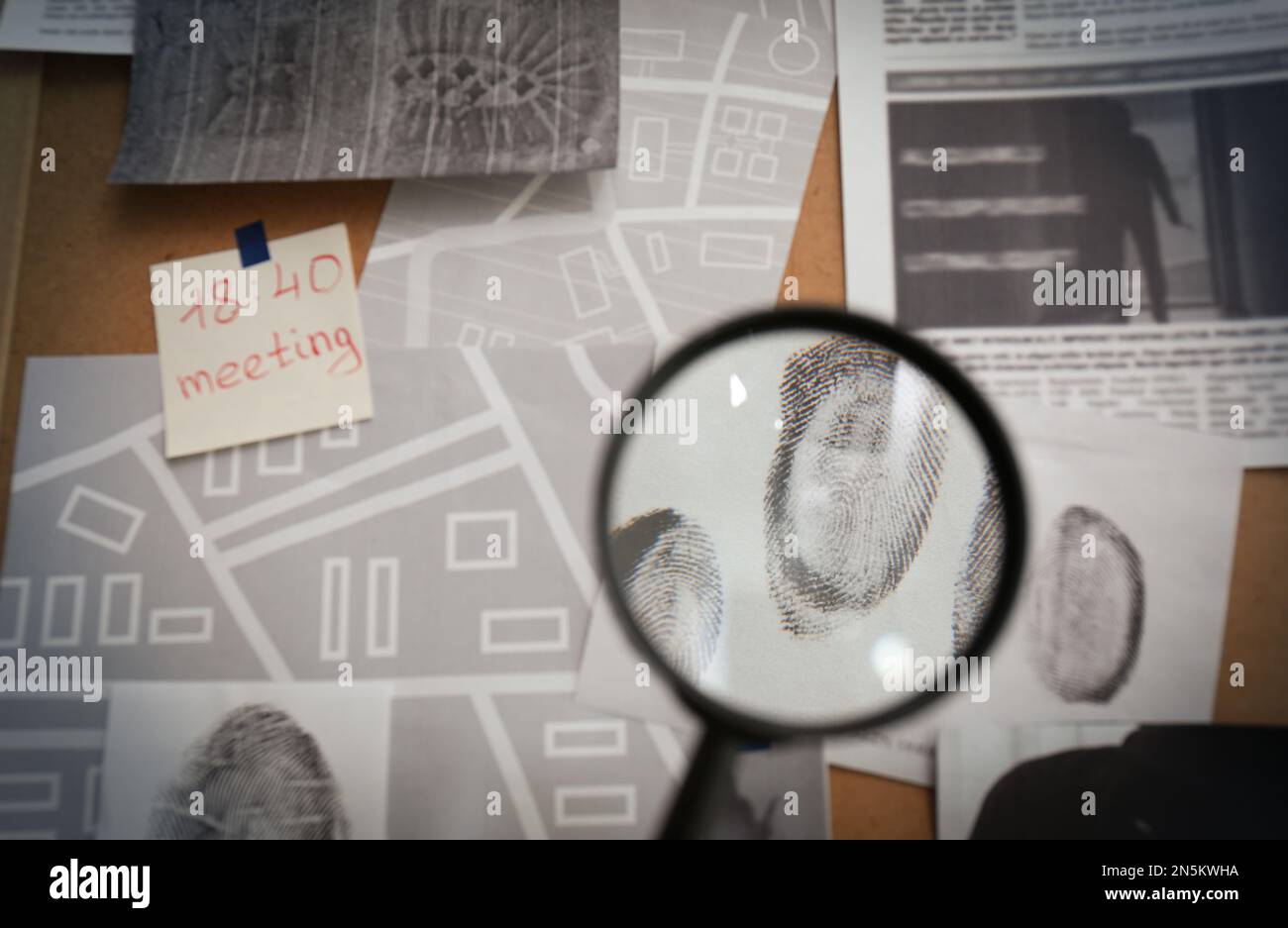 Regarder à travers la loupe les empreintes digitales sur le tableau de détective, gros plan Banque D'Images