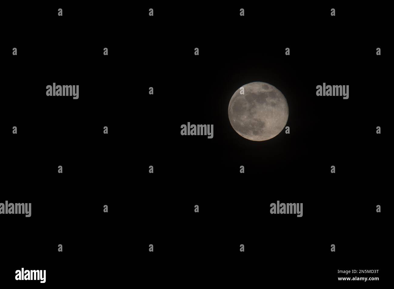 Une pleine lune filmée dans un ciel sombre et sans nuages au printemps au-dessus des chutes Taylors, Minnesota, États-Unis Banque D'Images