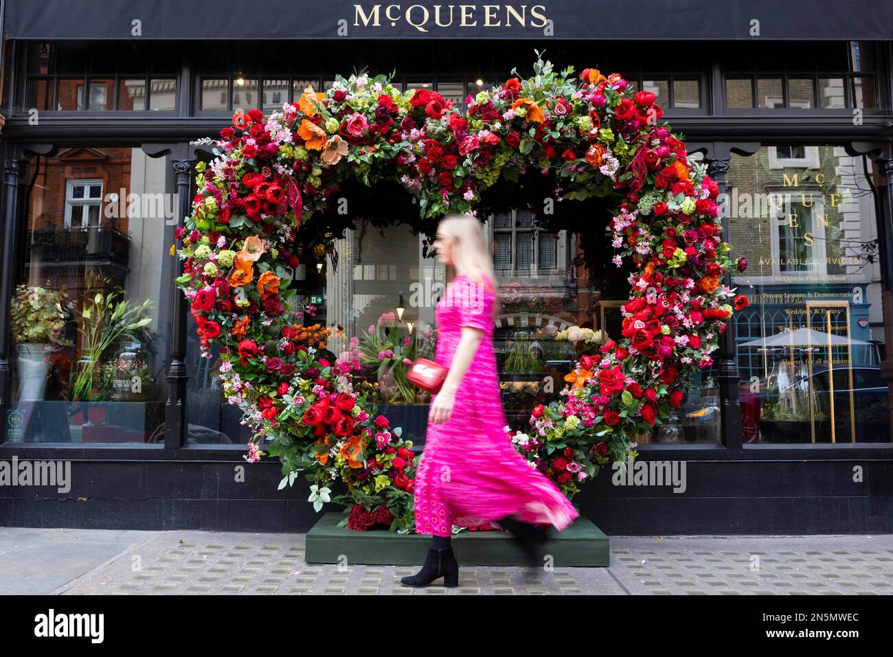 UTILISATION ÉDITORIALE UNE personne passe devant un nouvel étalage floral immersif à l'extérieur de l'école de fleurs McQueens à Mayfair pour célébrer la Saint-Valentin. Date de la photo: Jeudi 9 février 2023. Banque D'Images