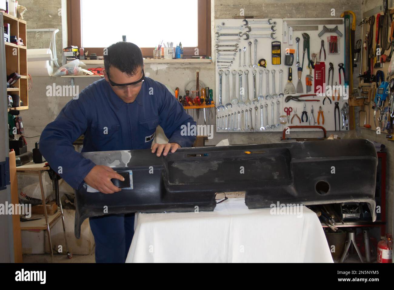 Image d'un réparateur de carrosserie automobile dans son atelier de réparation et de polissage d'un pare-chocs de voiture Banque D'Images