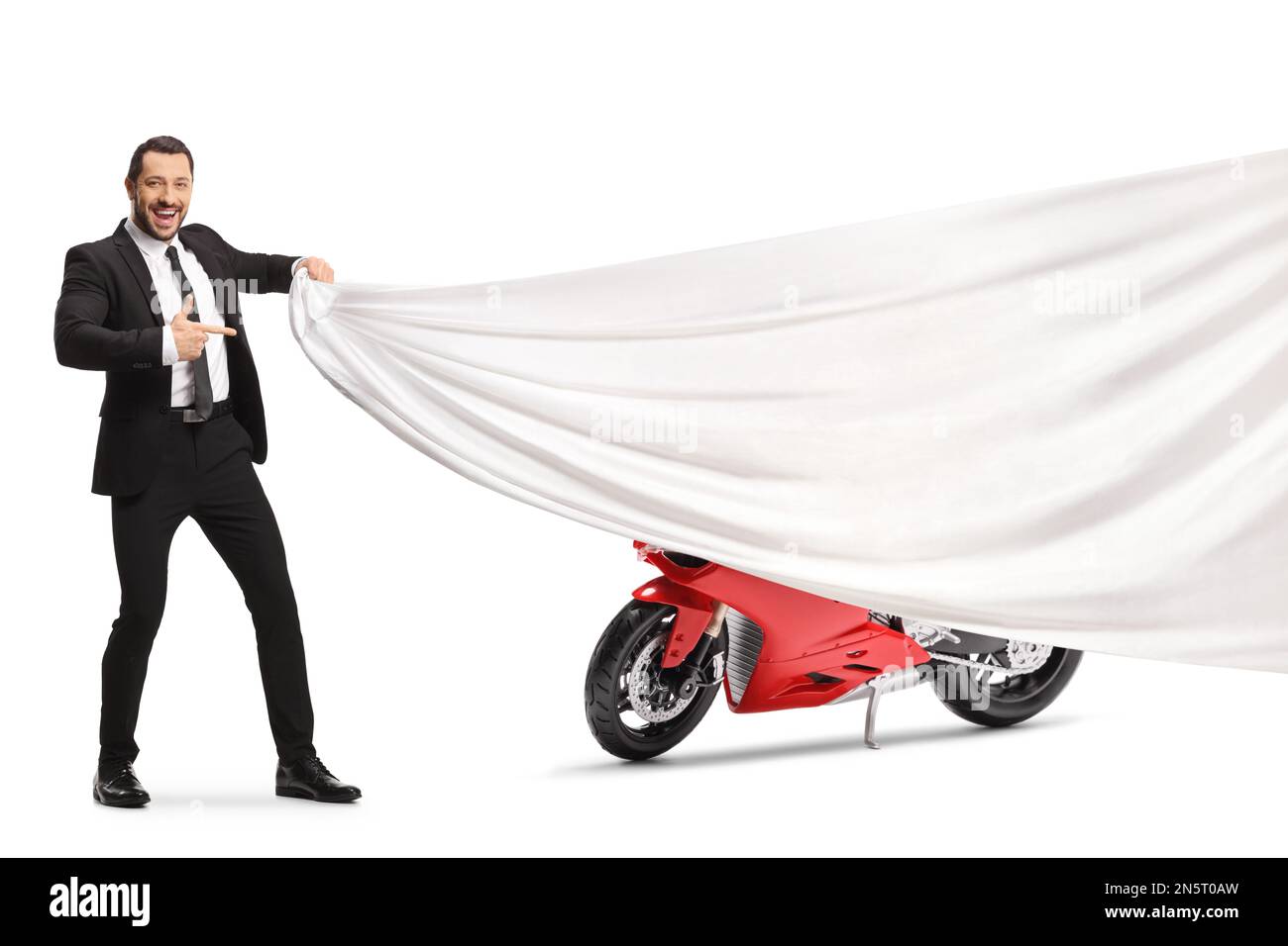 Homme en costume et cravate tenant un morceau de tissu blanc devant une moto rouge et pointant isolé sur fond blanc Banque D'Images