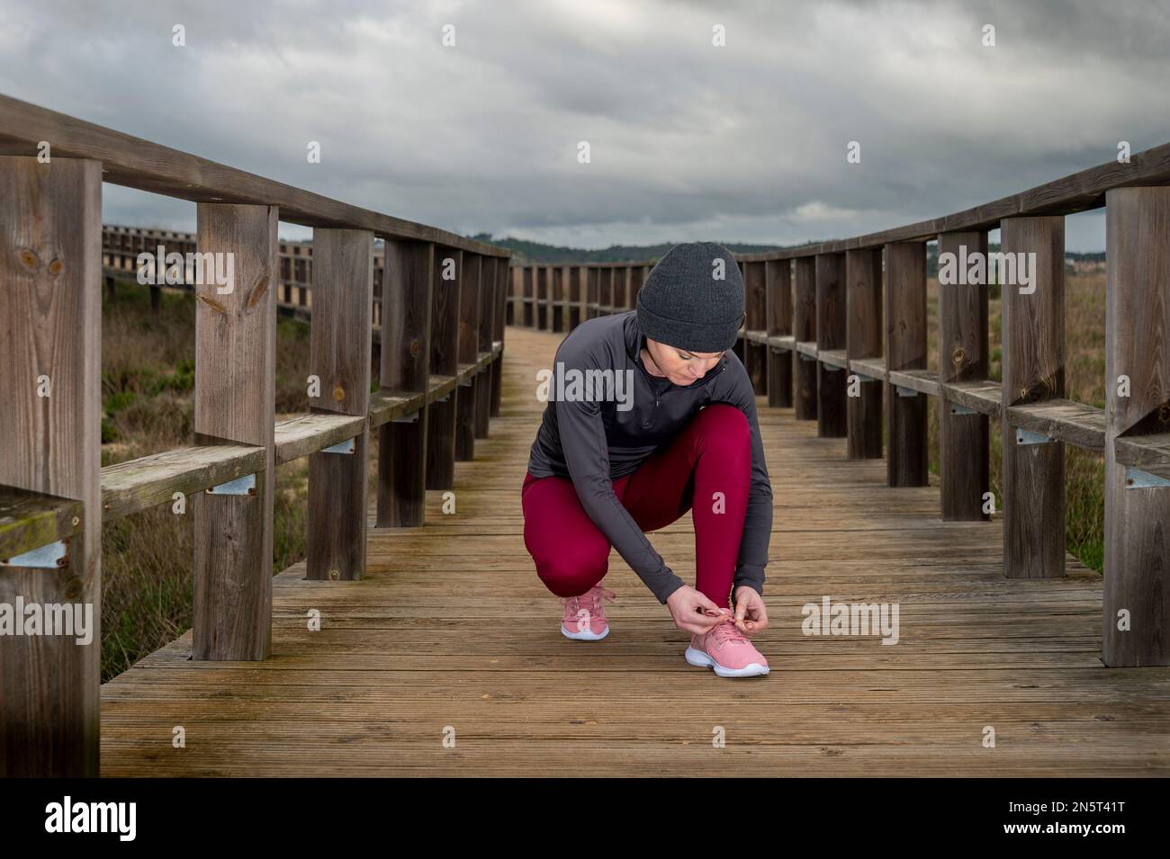 Une femme qui enjambe son cordonnet, preteration pour une course sur une promenade en bois Banque D'Images