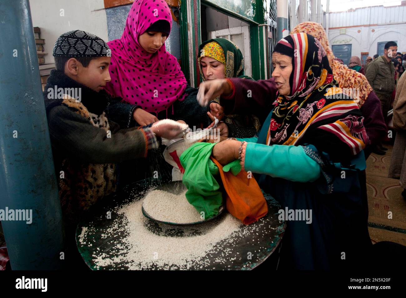 Kashmiri Muslims women collect rice as holy offerings inside the shrine ...