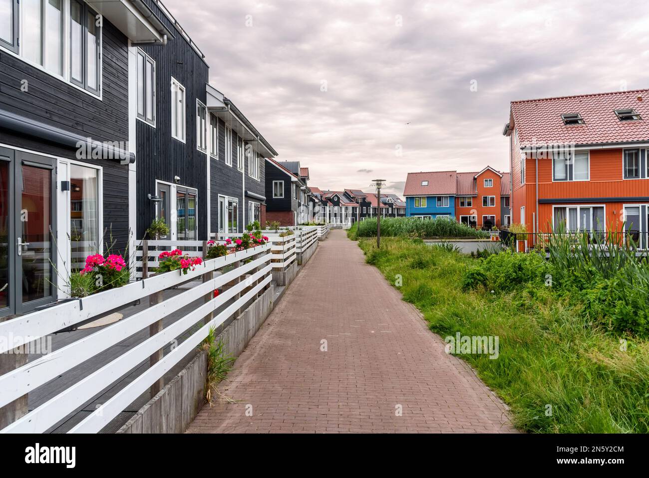 Maisons mitoyennes avec panneaux solaires sur le toit le long d'un sentier pavé déserté par une journée nuageux Banque D'Images