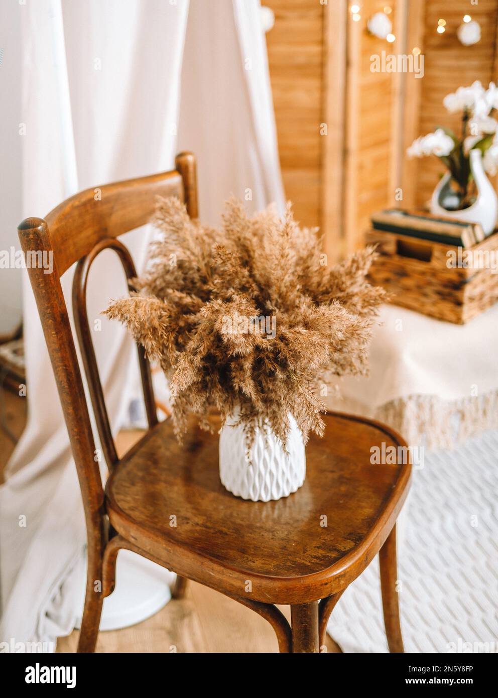 Cette chambre blanche et beige est décorée dans un style scandinave et boho. Pampas herbe dans le bouquet, chaise vintage, confortable et doux Banque D'Images