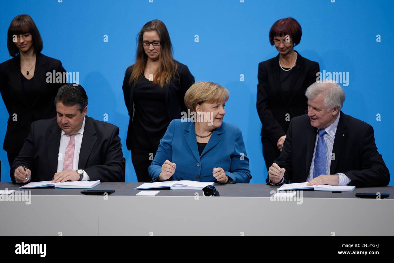 Sigmar Gabriel, chairman of the Social Democratic party SPD and designated economy minister, German Chancellor and chairwoman of the Christian Democratic Party CDU Angela Merkel and Bavarian Governor Horst Seehofer, chairman of the Bavarian Christian Social Union, CSU, , from left, sign the treaty for a new German 'grand coalition' government in Berlin, Germany, Monday, Dec. 16, 2013. (AP Photo/Michael Sohn) Banque D'Images