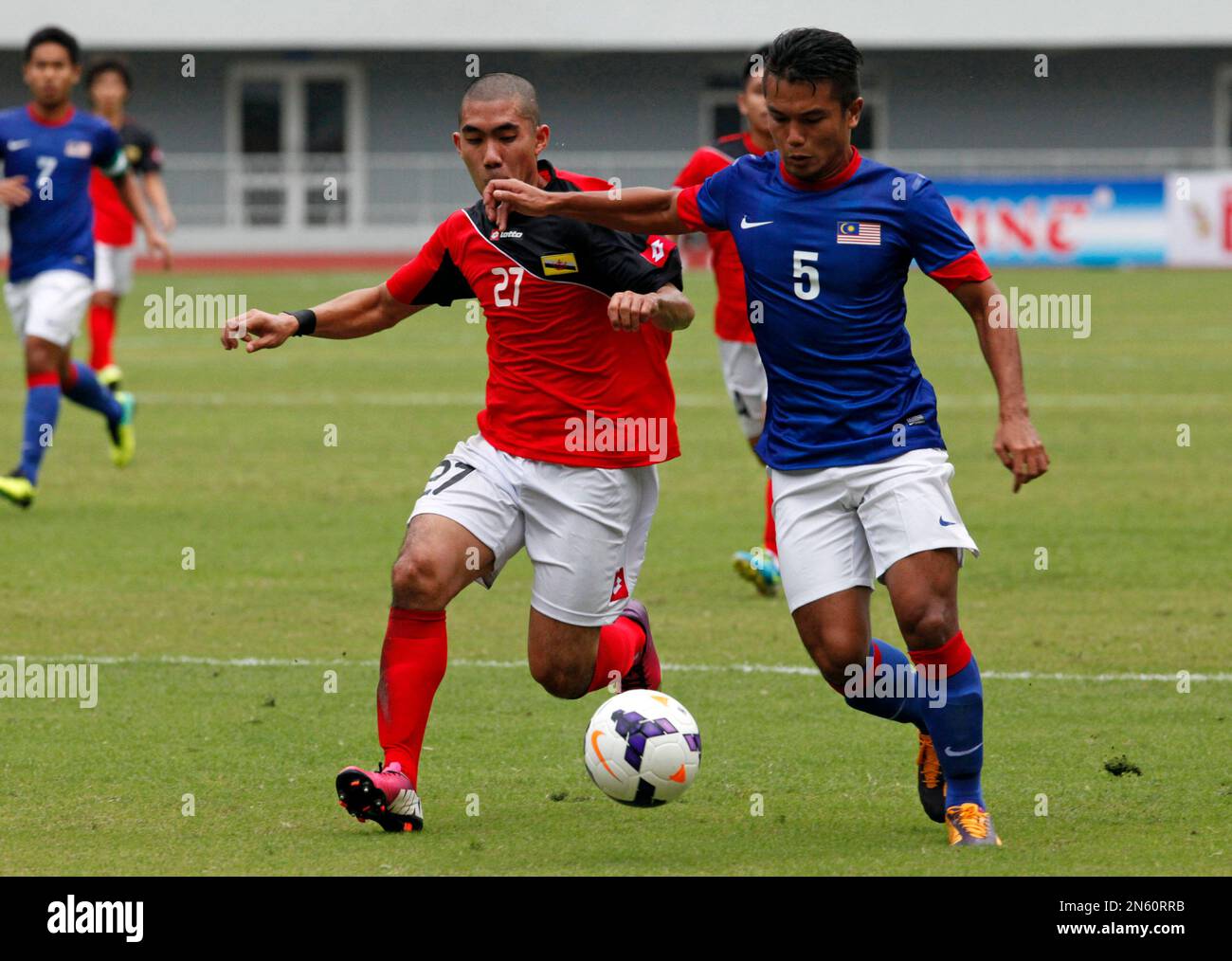 Azri Zahari of Brunei, red, vies the ball with Ashri Chuchu of Malaysia, blue, during a soccer match at the 27th SEA Game in Naypyitaw, Myanmar, Tuesday, Dec. 10, 2013. Malaysia beat Brunei with 2-0. (AP Photo/Khin Maung Win) Banque D'Images