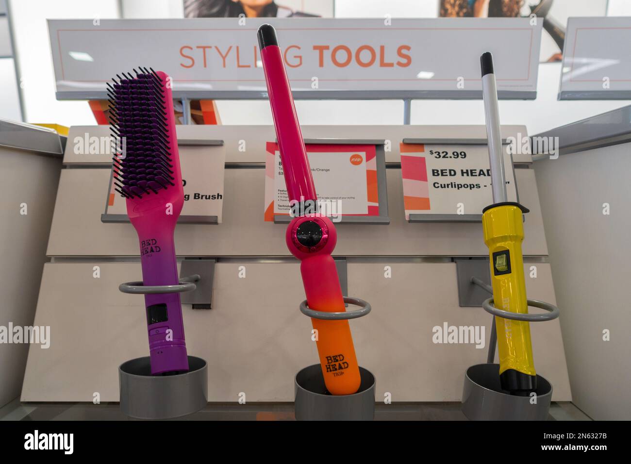 Les outils de coiffage de la tête de lit, y compris une brosse et deux fers à friser sur une étagère de magasin. ÉTATS-UNIS. Banque D'Images