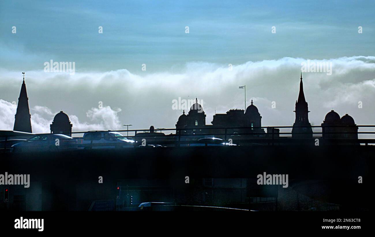 Vue sur la ville de Glasgow avec l'hôpital royal au sommet des tours de rue et des clochers d'église en silhouette vue depuis le survol de l'autoroute M8 Banque D'Images