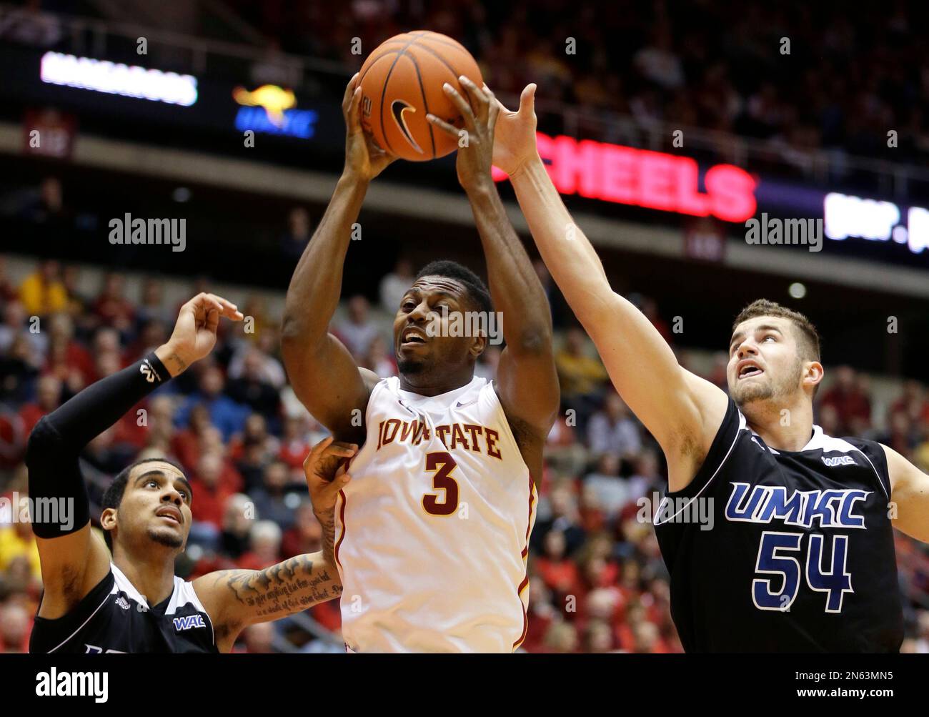 Iowa State forward Melvin Ejim, center, grabs a rebound between Missouri-Kansas City's Trinity Hall, left, and Isaac Kreuer during the first half of an NCAA college basketball game, Monday, Nov. 25, 2013, in Ames, Iowa. (AP Photo/Charlie Neibergall) Banque D'Images