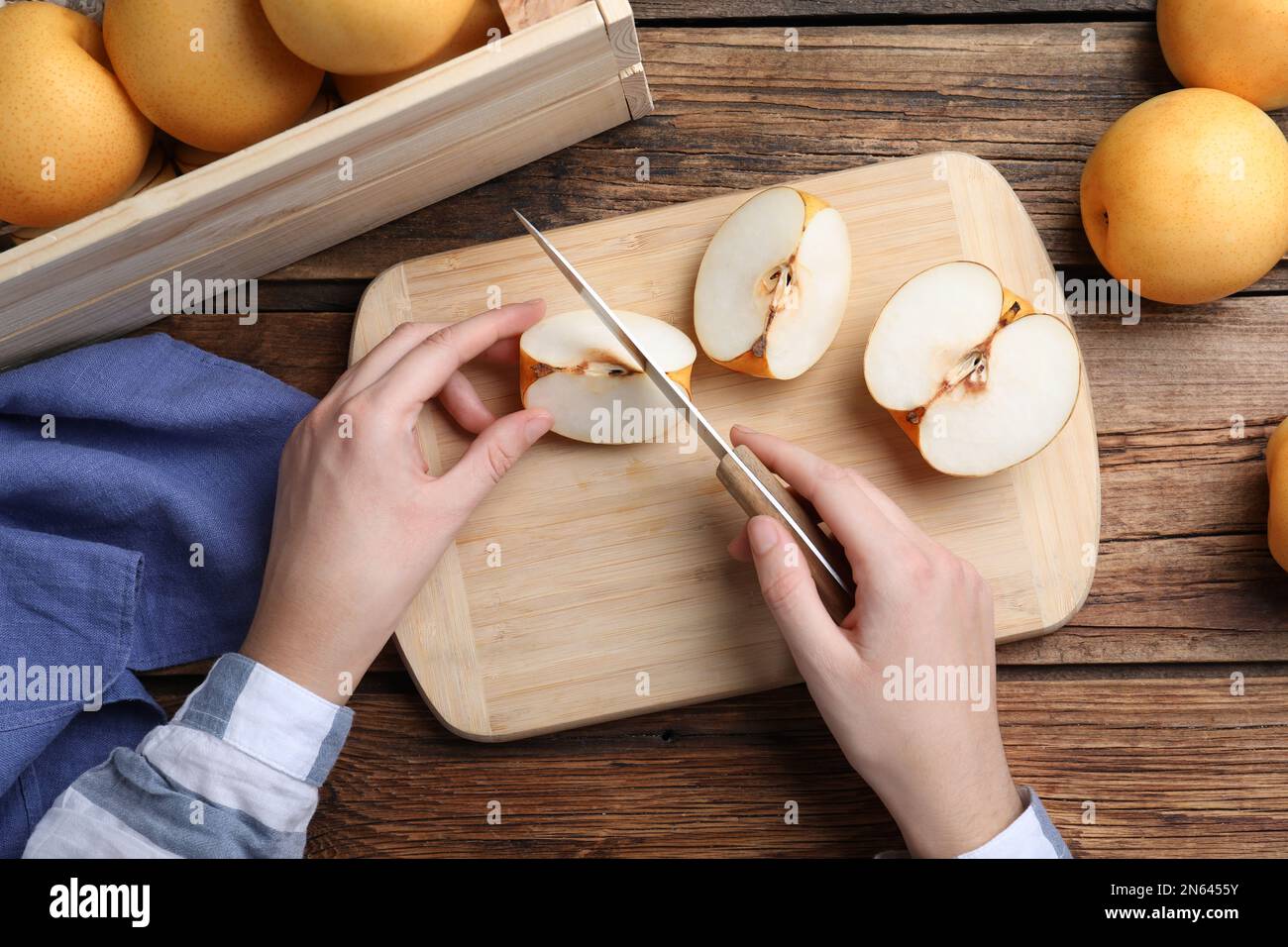 Femme coupant poire aux pommes à une table en bois, vue de dessus Banque D'Images