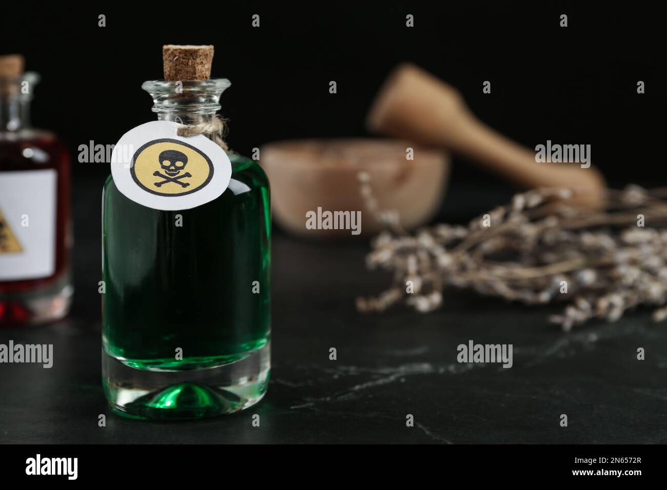 Bouteille de poison en verre avec panneau d'avertissement sur la table noire. Espace pour le texte Banque D'Images