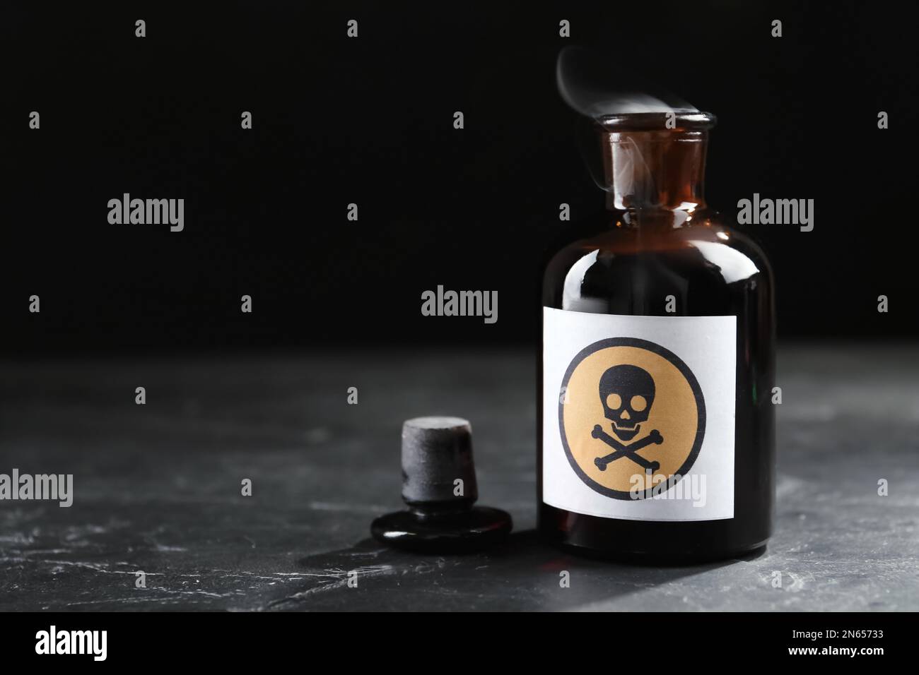 Ouvrir une bouteille de poison en verre avec un panneau d'avertissement sur la table noire. Espace pour le texte Banque D'Images