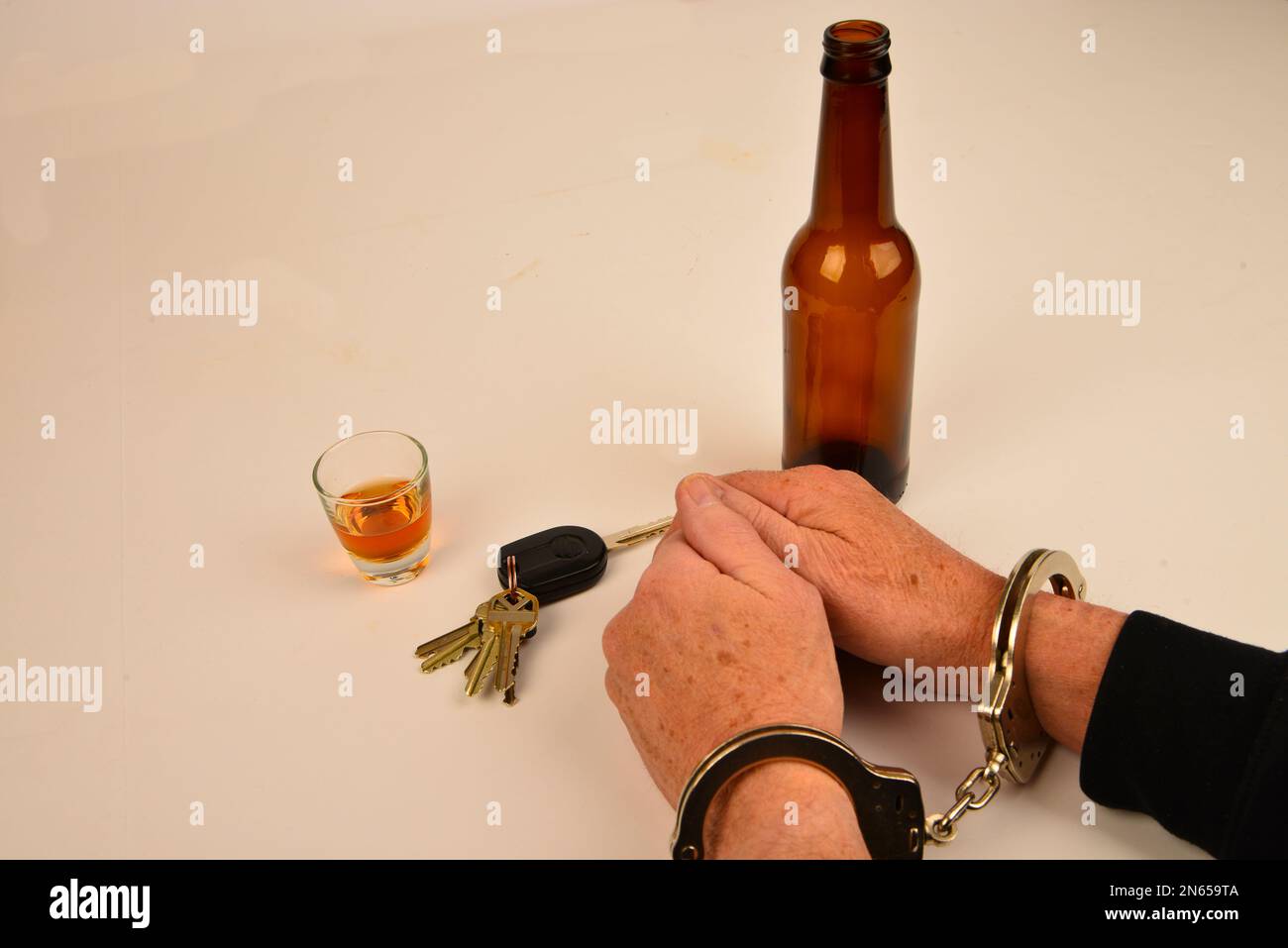 Poignets menottés avec clés de véhicule et contenants d'alcool symboles de consommation de substances et de conduite. Banque D'Images