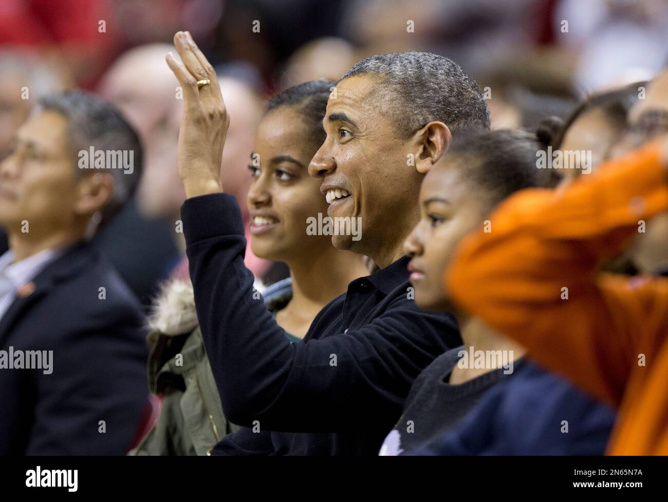 President Barack Obama, center, with first lady Michelle Obama, and their daughters Sasha, left of Pres. Obama, and Malia, right of Pres. Obama, and wave as they arrive at the Comcast Center in College Park, Md., to watch his brother-in-law Oregon State Beavers Coach Craig Robinson’s basketball team play against the Maryland Terrapins, Sunday, Nov. 17, 2013. (AP Photo/Manuel Balce Ceneta) Banque D'Images