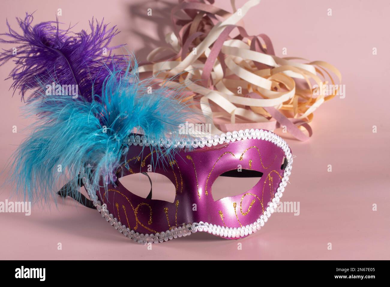 Masque de carnaval vénitien avec plumes et éléments typiques dans le fond rose Banque D'Images