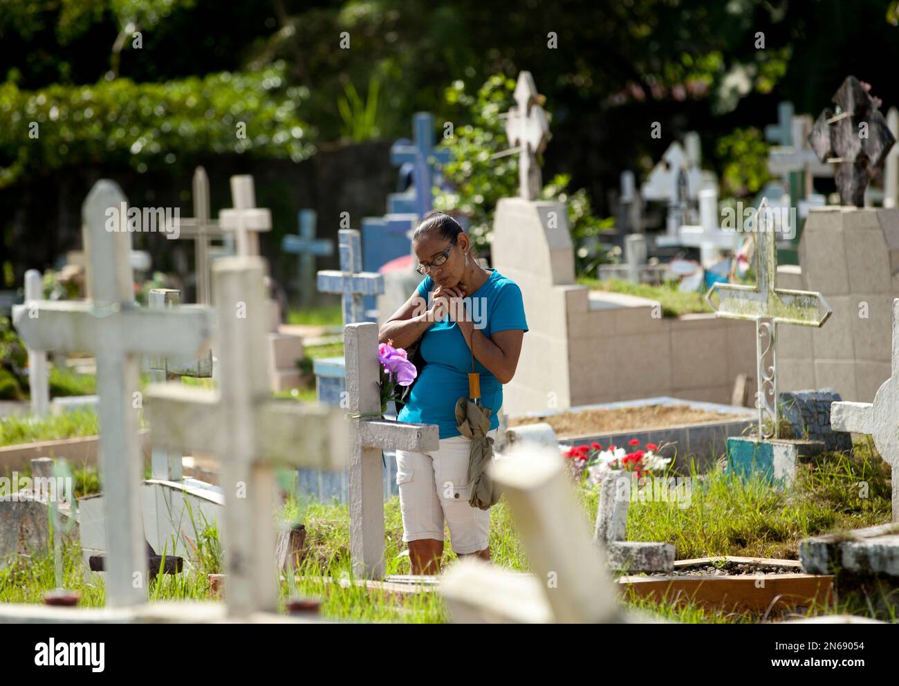 A woman prays as she visits a relative's grave marking the Day of the Dead holiday, at the Juan Diaz cemetery in Panama City, Saturday, Nov. 2, 2013. The souls of departed loved ones are being honored around Latin America as celebrants blend pre-Columbian rituals with the Roman Catholic observance of all Saint’s Day on Nov. 1 and All Soul’s Day on Nov. 2 to mark the Day of the Dead. (AP Photo/Arnulfo Franco) Banque D'Images