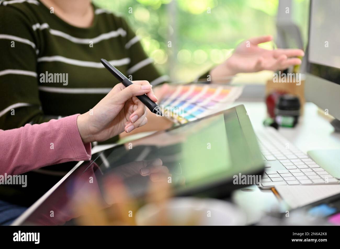 Image rognée de deux femmes asiatiques graphistes travaillant ensemble au bureau, à l'aide d'une tablette graphique, à la conception de nouveaux produits, de brainstorming et de sha Banque D'Images