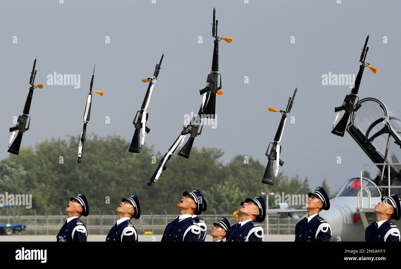 Members of a South Korean Air Force honor guard throw their guns in the air during a press day of an air show as part of the Seoul International Aerospace & Defense Exhibition which will be held from Oct. 25 to Nov. 3, at Cheongju International Airport in Cheongju, south of Seoul, South Korea, Thursday, Oct. 24, 2013. (AP Photo/Lee Jin-man) Banque D'Images