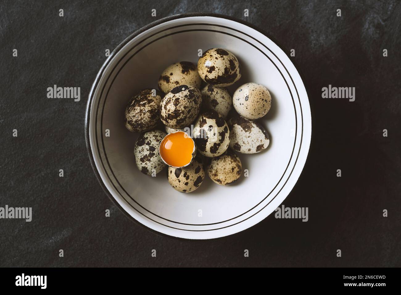 Œufs de caille frais bio gratuits dans un bol en céramique sur fond rustique noir. Vue de dessus. Banque D'Images
