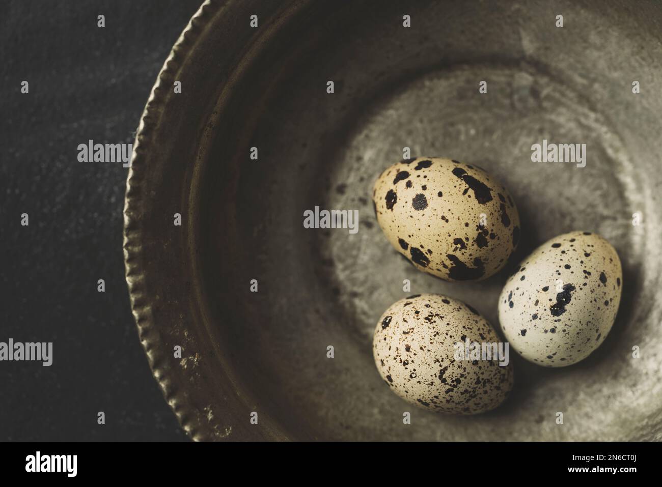 Œufs de caille frais bio gratuits dans un bol en cuivre sur fond rustique noir. Vue de dessus. Banque D'Images