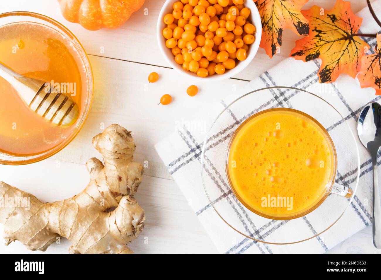 Thé au jus d'argousier avec gingembre et miel sur fond de bois clair. Concept-boisson de vitamine d'automne pour la promotion de la santé. Mise à plat. Vue de dessus. Banque D'Images