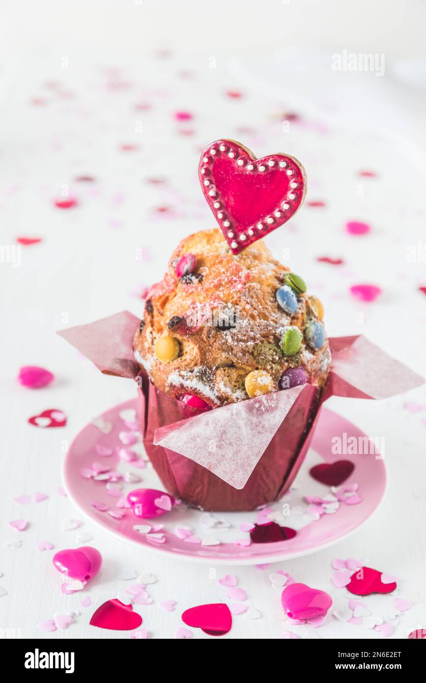 Muffin aux grains de chocolat, décoré de coeurs rouges, roses et blancs pour les anniversaires ou les jours de la Saint-Valentin, fond blanc, vertical Banque D'Images