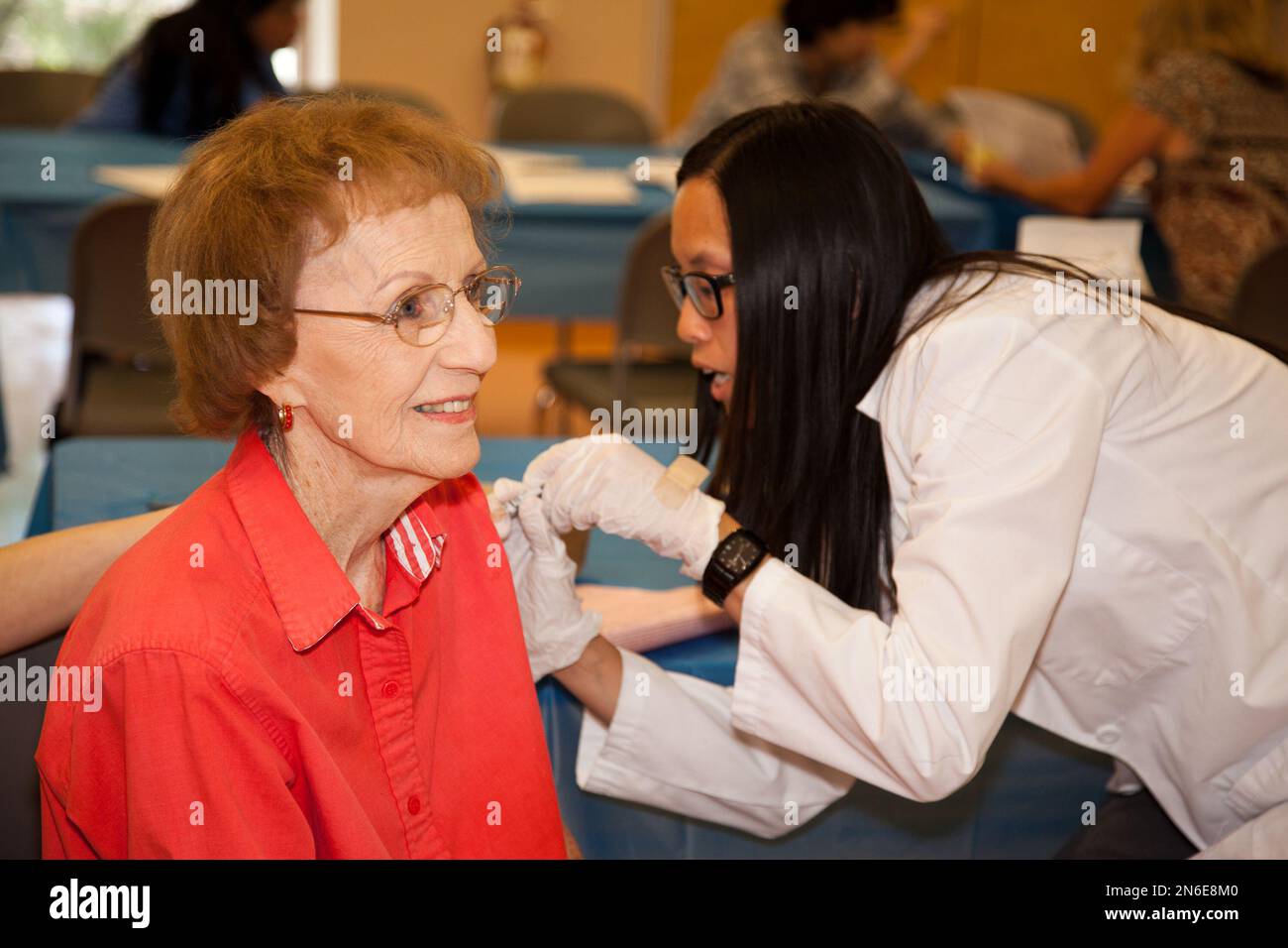 Pharmacist Jill Ruth Nguyen, right, gives Maxine Ijams a flu shot during the Flu + You event at Ellie Towne Flowing Wells Center, sponsored by the National Council on Aging and Sanofi Pasteur on Tuesday, Oct. 8, 2013, in Tucson, Ari. (Madison Kirkman/ AP Images for National Council on Aging and Sanofi Pasteur) Banque D'Images