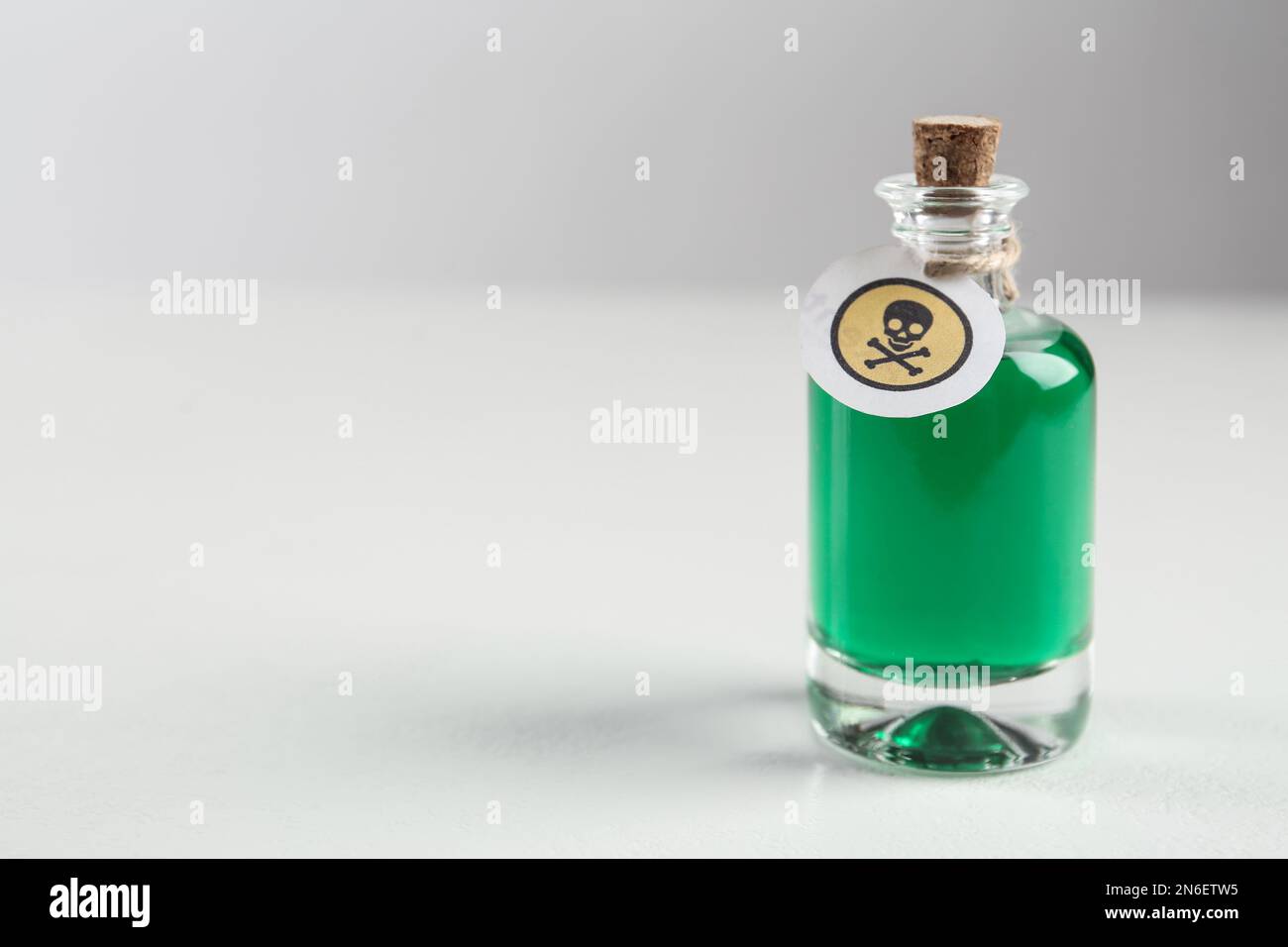 Bouteille de poison en verre avec panneau d'avertissement sur fond clair. Espace pour le texte Banque D'Images